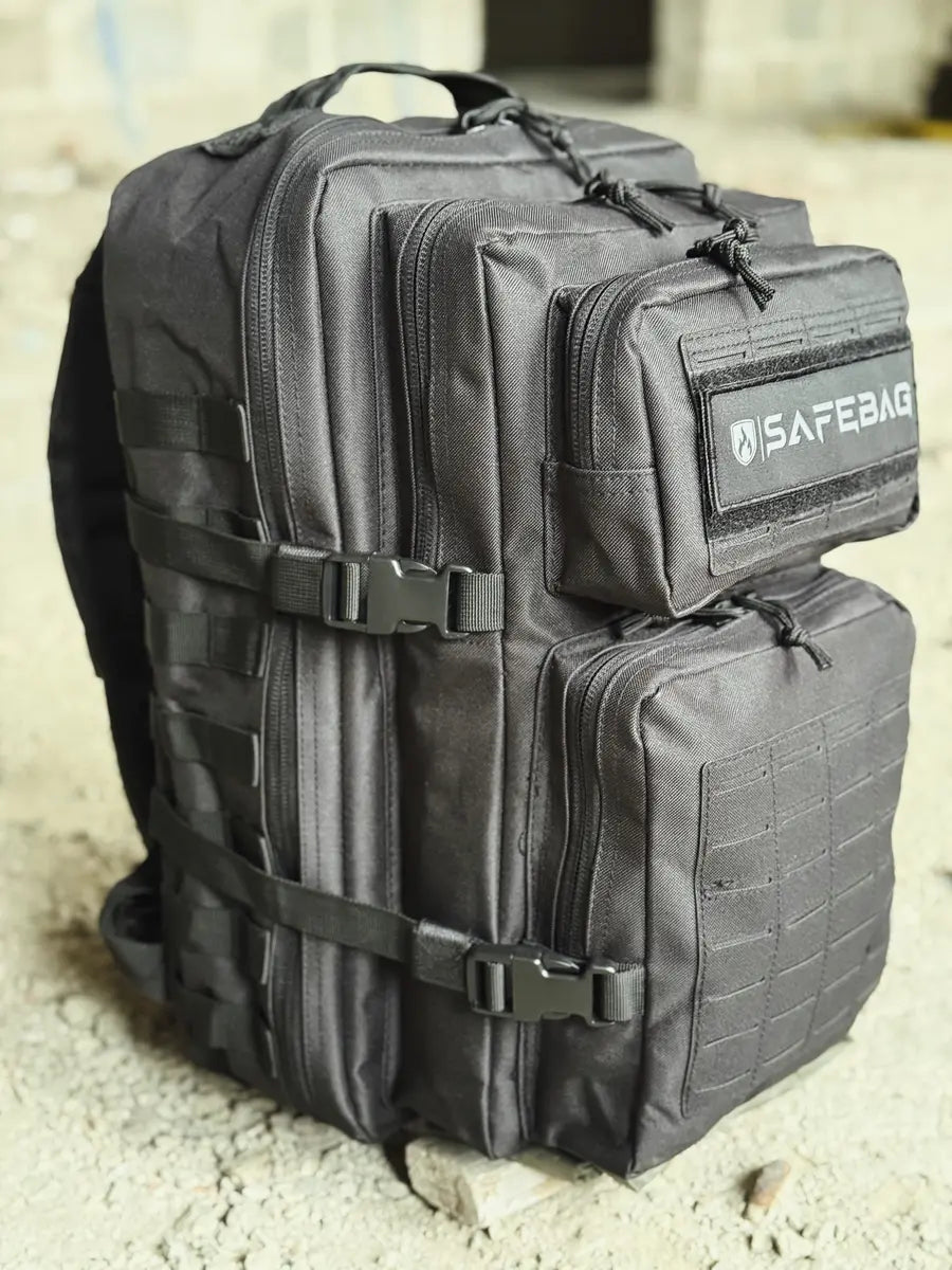 Black tactical backpack with visible 'SAFERAG' branding on a concrete surface.